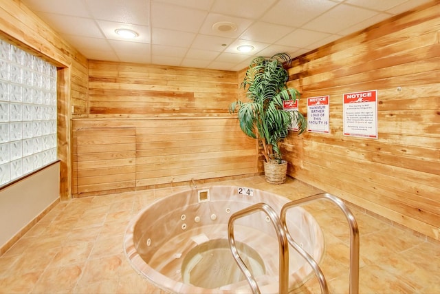 room details featuring wood walls and a drop ceiling