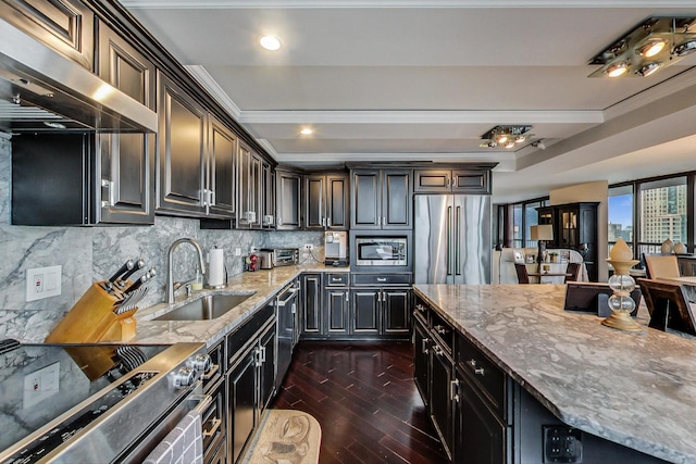 kitchen featuring light stone counters, a sink, appliances with stainless steel finishes, ventilation hood, and dark wood finished floors