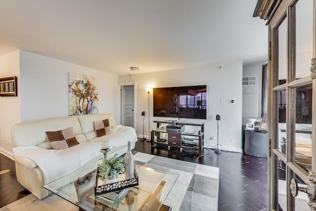 living room with wood finished floors, visible vents, and baseboards