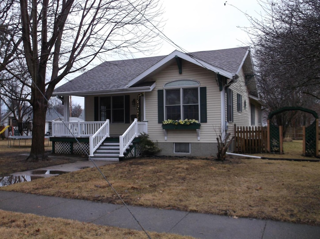 view of front of house featuring roof with shingles, a trampoline, and a front yard