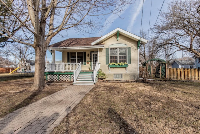 view of front of property with a porch, a trampoline, fence, and roof with shingles