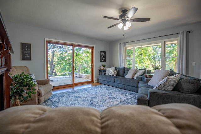 living area with ceiling fan, a fireplace, and wood finished floors