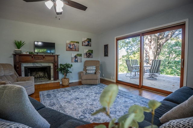 living area featuring a ceiling fan, wood finished floors, a high end fireplace, and baseboards