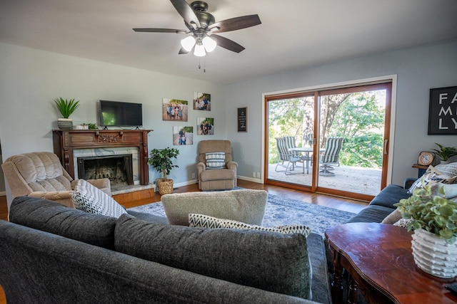 living room with ceiling fan, a fireplace, wood finished floors, and baseboards