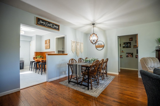 dining space with a chandelier, wood-type flooring, and baseboards