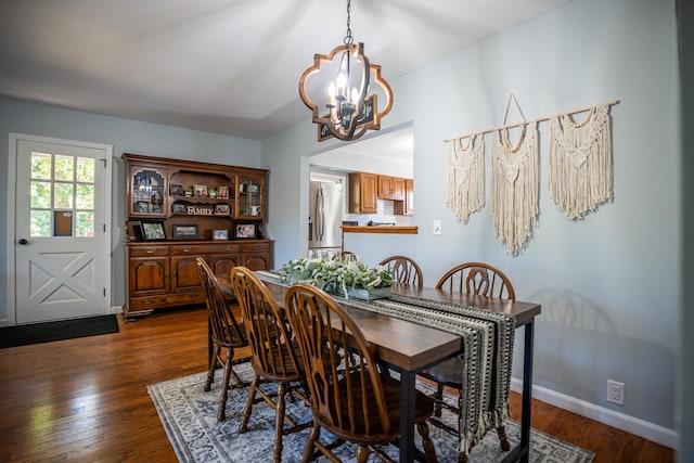 dining space with dark wood-style floors, baseboards, and an inviting chandelier