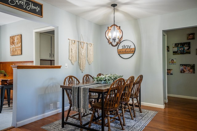 dining space featuring baseboards, wood finished floors, and an inviting chandelier