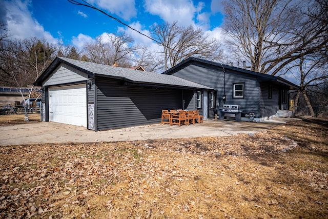 exterior space with a garage, a patio, a shingled roof, and fence