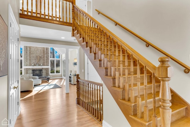 stairs featuring a fireplace, a high ceiling, and wood finished floors