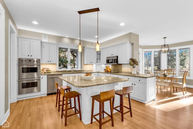 kitchen with a center island, a breakfast bar area, stainless steel appliances, a wealth of natural light, and light wood-style flooring