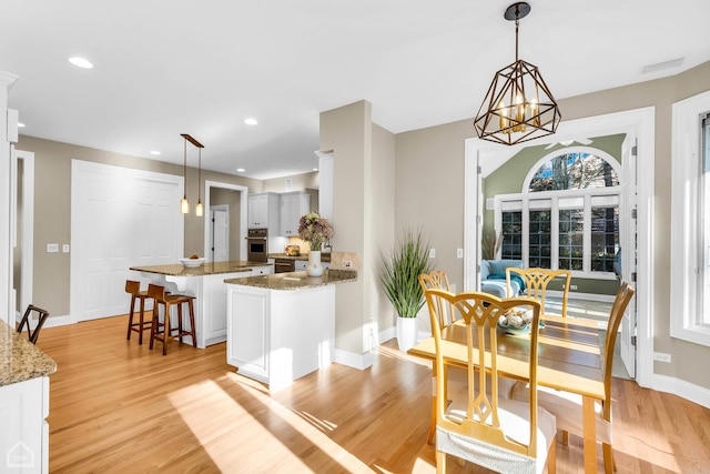 dining room with light wood-style floors, baseboards, a notable chandelier, and recessed lighting