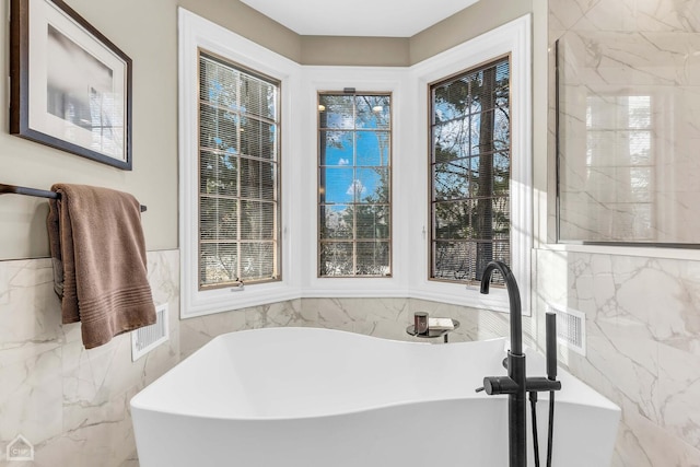 bathroom featuring a soaking tub, tile walls, and a sink