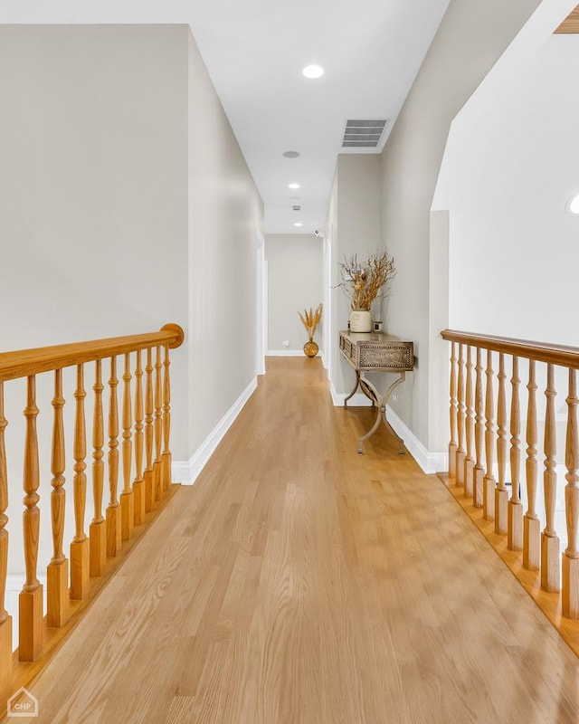 hallway with recessed lighting, wood finished floors, visible vents, and baseboards