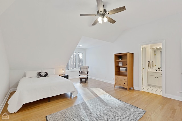 bedroom featuring lofted ceiling, connected bathroom, light wood-style flooring, and baseboards