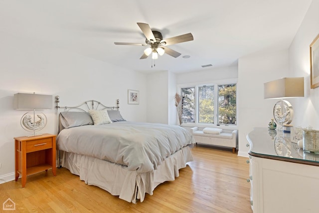 bedroom featuring light wood finished floors, ceiling fan, visible vents, and baseboards