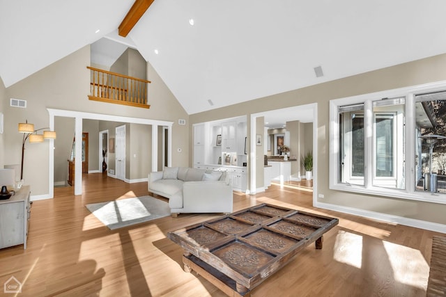 living room with visible vents, high vaulted ceiling, light wood-type flooring, beamed ceiling, and baseboards