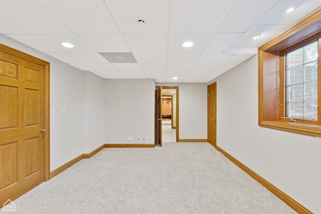 below grade area featuring recessed lighting, light colored carpet, a paneled ceiling, and baseboards