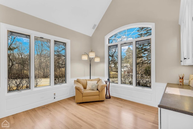 sitting room featuring lofted ceiling, wainscoting, and a healthy amount of sunlight