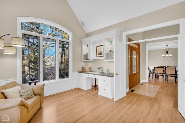 sitting room with light wood-style floors, visible vents, a notable chandelier, and built in desk