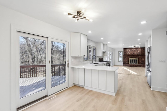 kitchen featuring stainless steel appliances, a peninsula, a sink, and light wood-style flooring