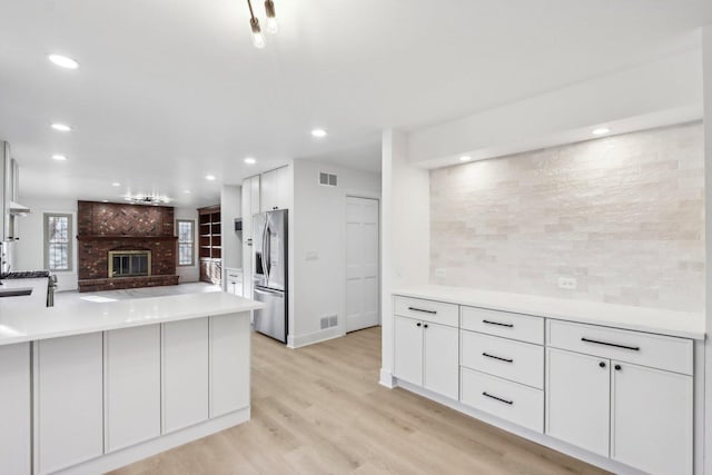 kitchen featuring light wood finished floors, visible vents, white cabinets, and stainless steel fridge with ice dispenser