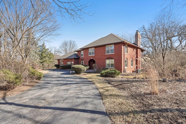 view of front of property featuring a chimney, aphalt driveway, and brick siding