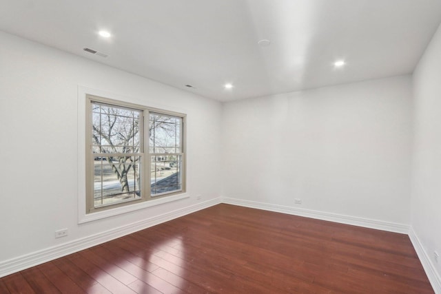 empty room with baseboards, visible vents, and dark wood finished floors