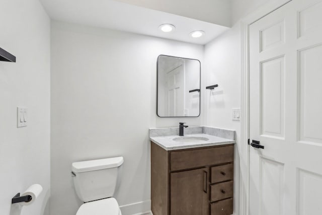 bathroom featuring baseboards, vanity, and toilet