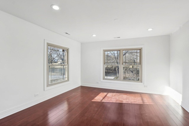 spare room featuring a wealth of natural light, hardwood / wood-style flooring, and baseboards