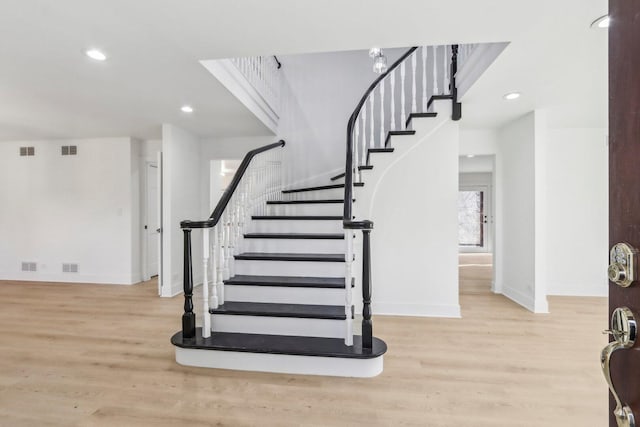 stairway with visible vents, baseboards, and wood finished floors