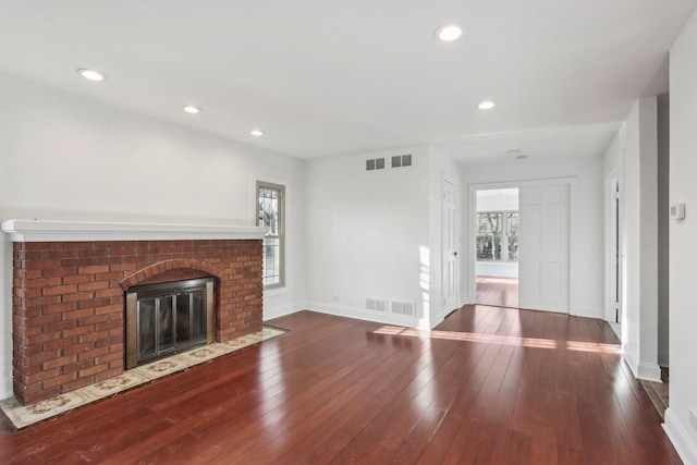 unfurnished living room with recessed lighting, a fireplace, visible vents, baseboards, and hardwood / wood-style floors