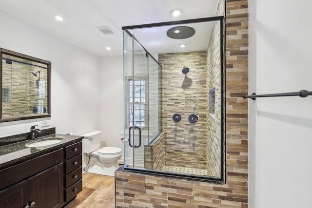 full bathroom with toilet, wood finished floors, visible vents, vanity, and a stall shower