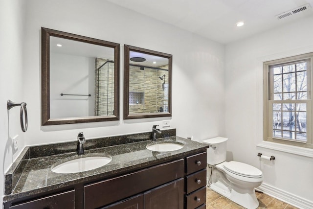 full bathroom featuring visible vents, a sink, a tile shower, and toilet