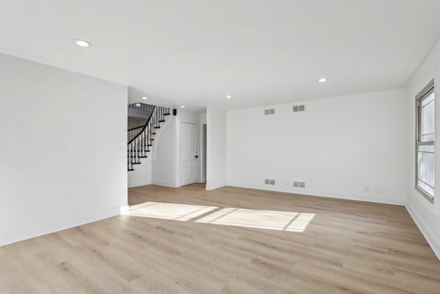 spare room with stairs, wood finished floors, and visible vents