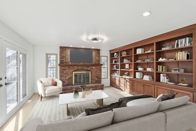 living area with recessed lighting, a brick fireplace, and light wood-style flooring