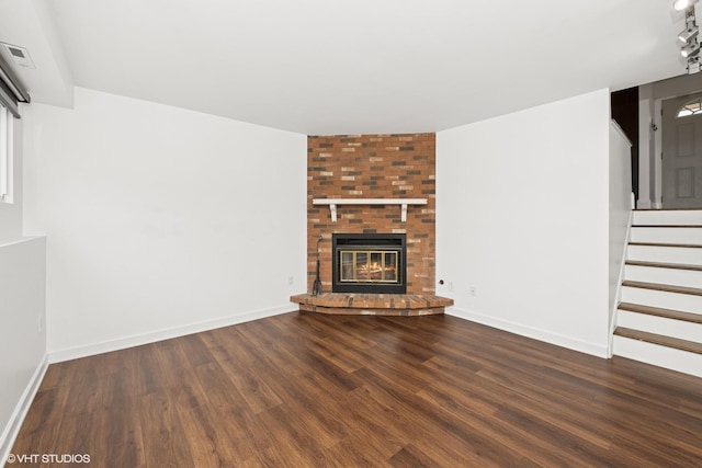 unfurnished living room featuring wood finished floors, a fireplace, baseboards, and stairs