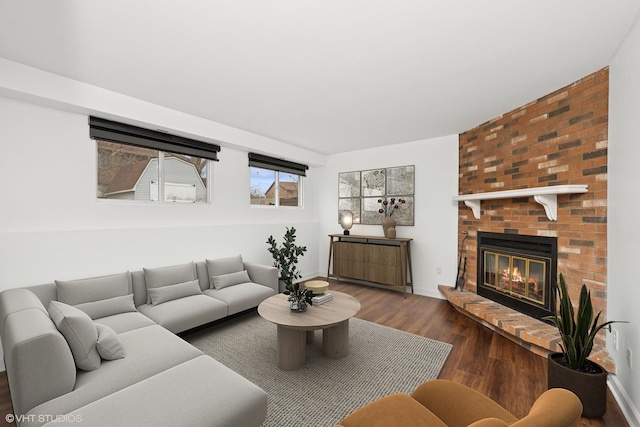 living area featuring a fireplace, baseboards, and wood finished floors