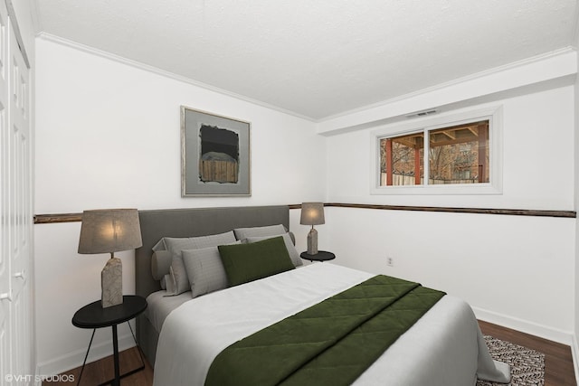 bedroom with dark wood-style floors, visible vents, a textured ceiling, and baseboards