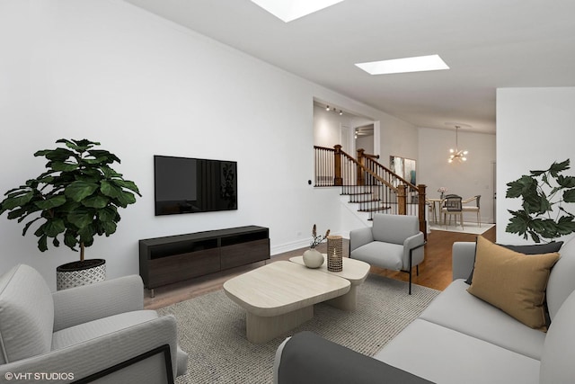 living area with a skylight, wood finished floors, a chandelier, baseboards, and stairs