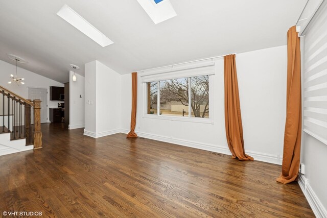 unfurnished living room featuring wood finished floors, baseboards, stairway, lofted ceiling with skylight, and an inviting chandelier