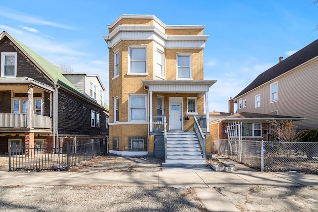 townhome / multi-family property with covered porch, brick siding, and fence