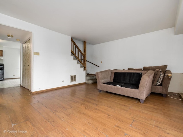 living room featuring visible vents, baseboards, stairs, and light wood-style floors