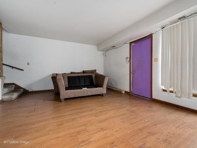 living area featuring stairs, light wood-style flooring, and baseboards