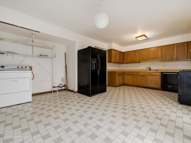 kitchen with black appliances, a sink, washer / clothes dryer, brown cabinetry, and light countertops