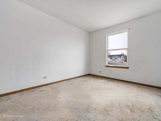 carpeted spare room featuring baseboards