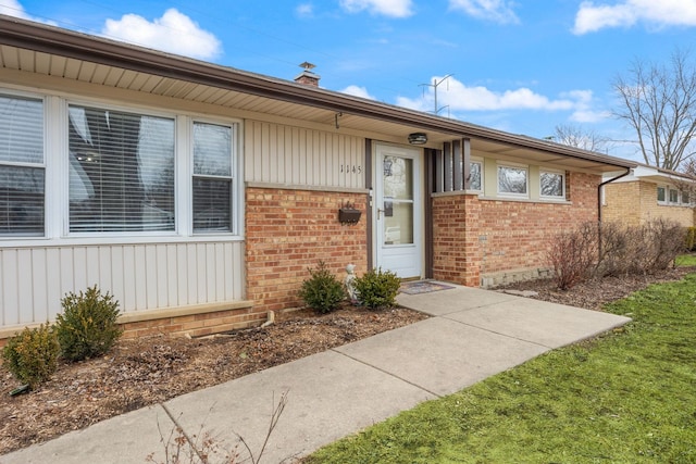 doorway to property with a chimney and brick siding