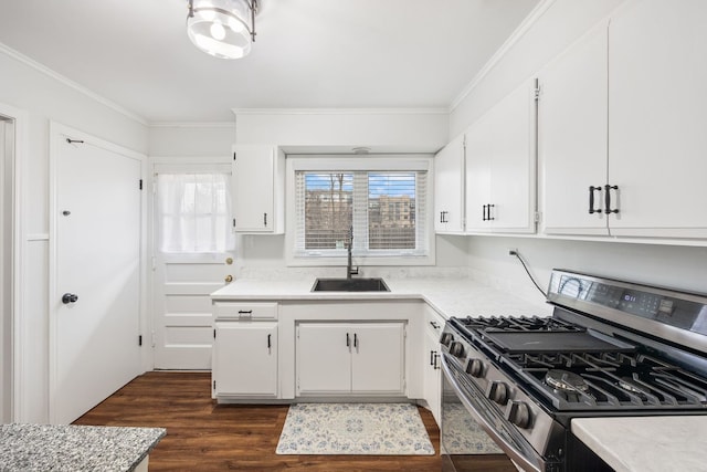 kitchen featuring light countertops, gas stove, a sink, and crown molding