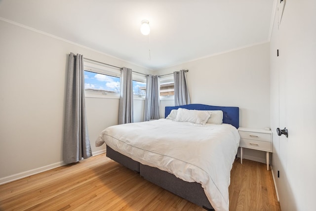 bedroom with crown molding, light wood-style flooring, and baseboards