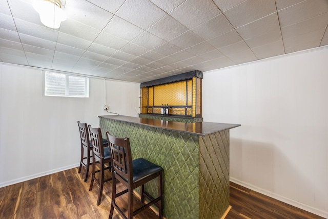 bar with baseboards, a bar, and wood finished floors