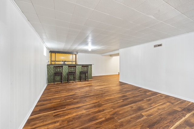 spare room featuring indoor bar, wood finished floors, and visible vents